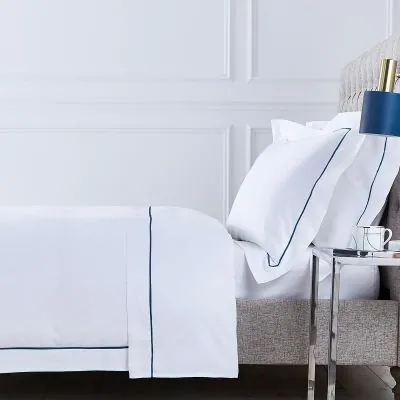 Hotel bed with white linen and navy piping